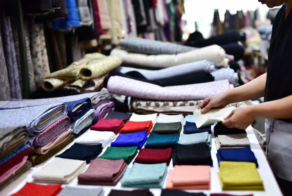 Hands-on fabric selection at Guangzhou market – practical material sourcing for cost-effective streetwear production.
